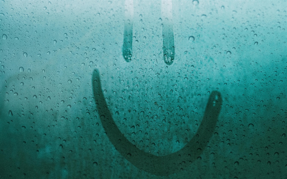 A damp window with a smile drawn into the water droplets by someone's finger