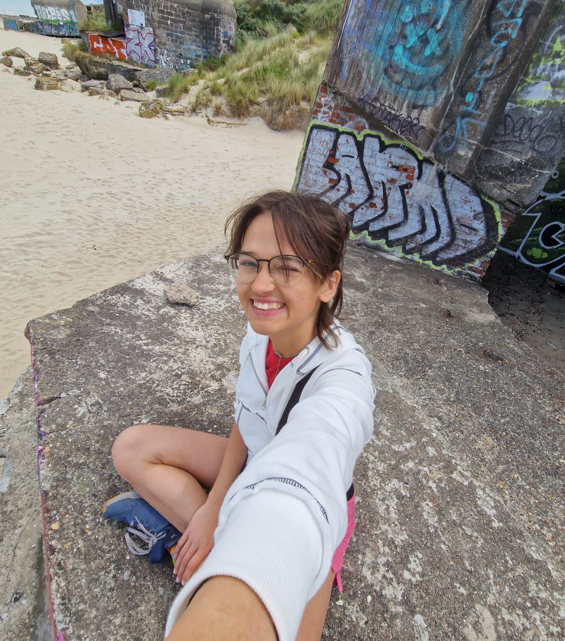 A photo of Ana sat on concrete with the beach in the background